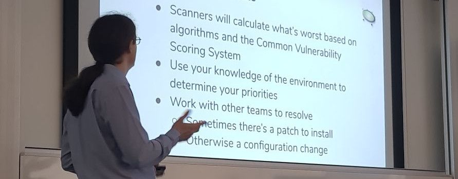 Photograph showing the back of Jonathan's head, while he looks at his slides being projected onto a screen. The slide talks about vulnerability scanning, but only some of it is visible in the photo.